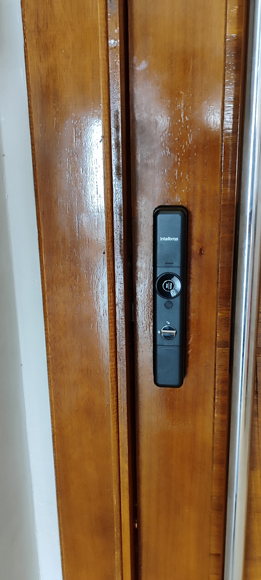 Intelbras com botão giratório em porta de madeira envernizada