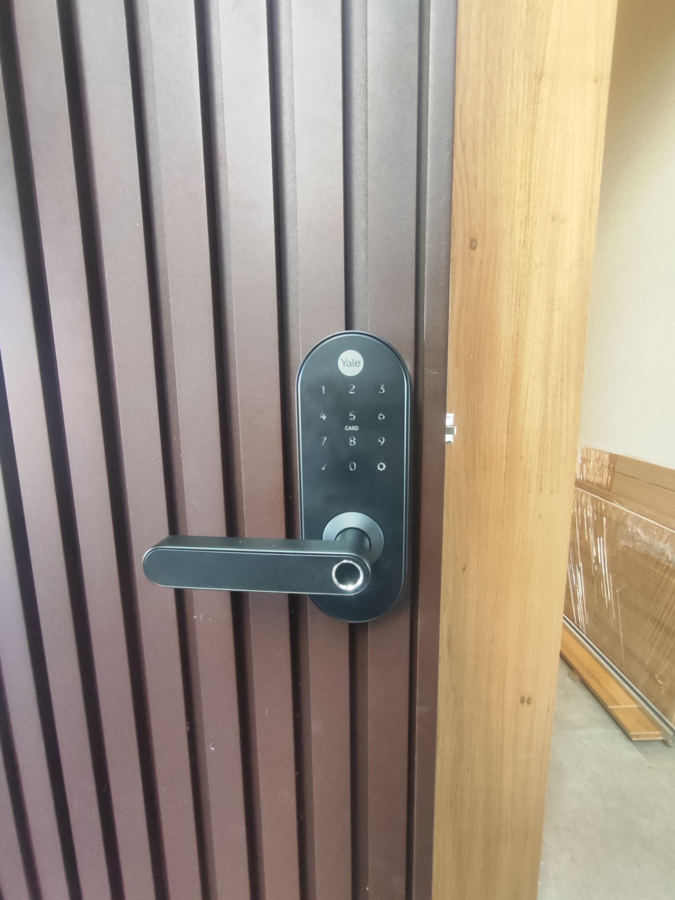 Yale com maçaneta e biometria em porta marrom ripada